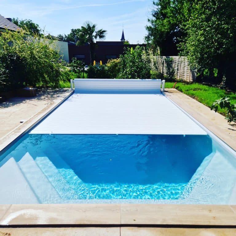 Piscine coque avec couverture automatique et eau cristalline à Nancy. Escalier intégré pour un accès facile.